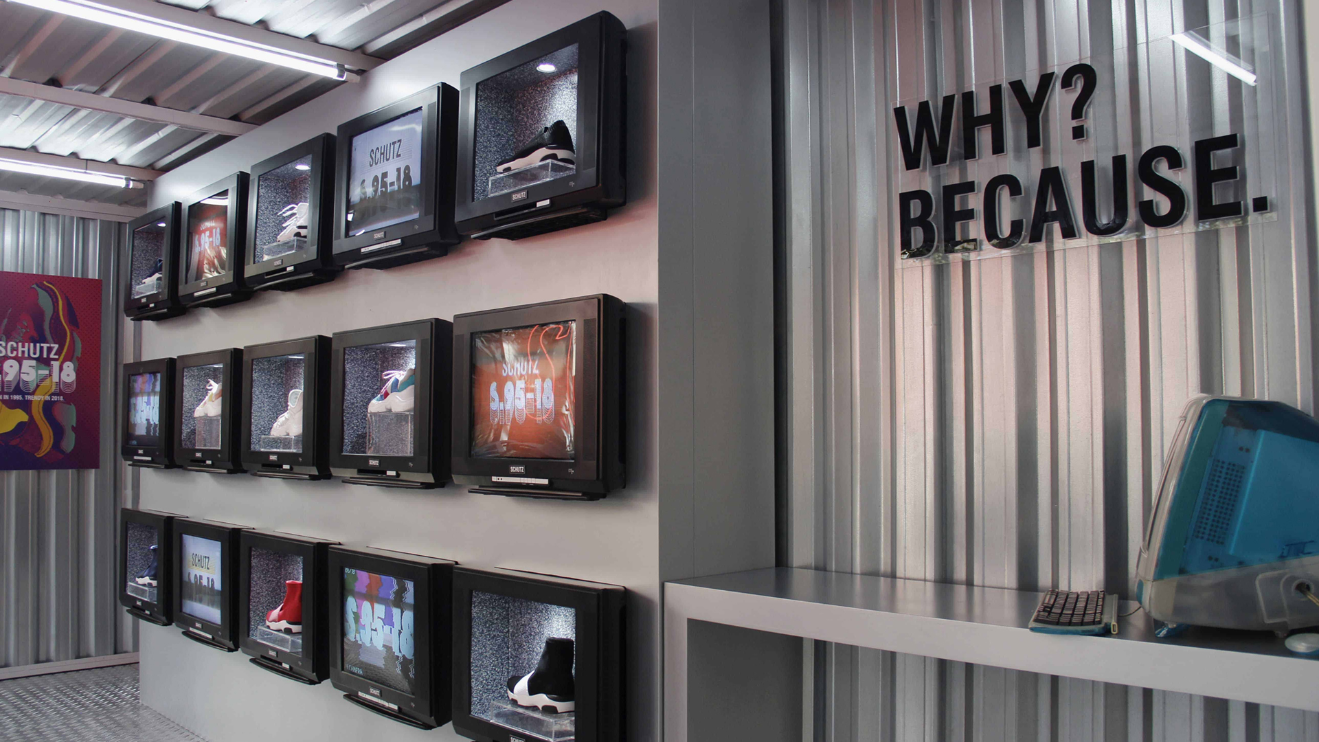 Foto tirada de dentro de um contâiner galvanizado, mostrando a marca Shutz. Várias televisões antigas mostram imagens diferentes.